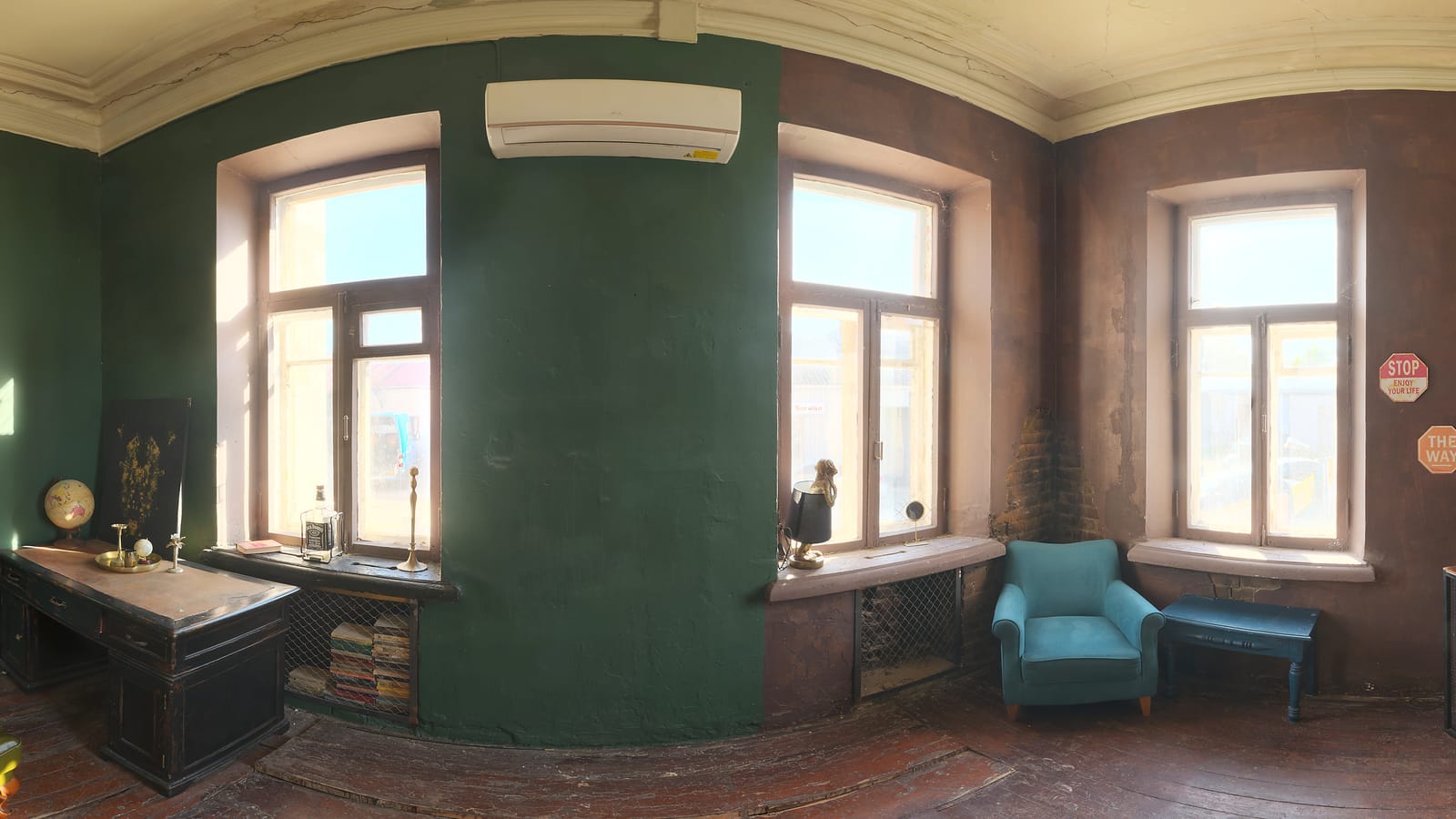 Vue d’ensemble panoramique d’un intérieur : murs vert profond, hautes fenêtres, parquet ancien et moulures