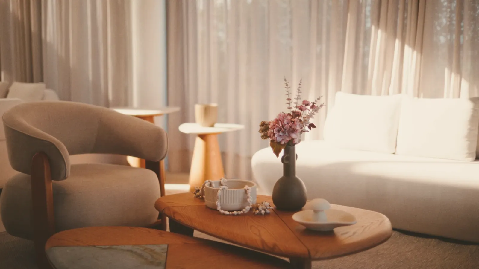 The furnished space: enveloping bouclé armchair, solid wood coffee table, rounded white sofa, linen curtains