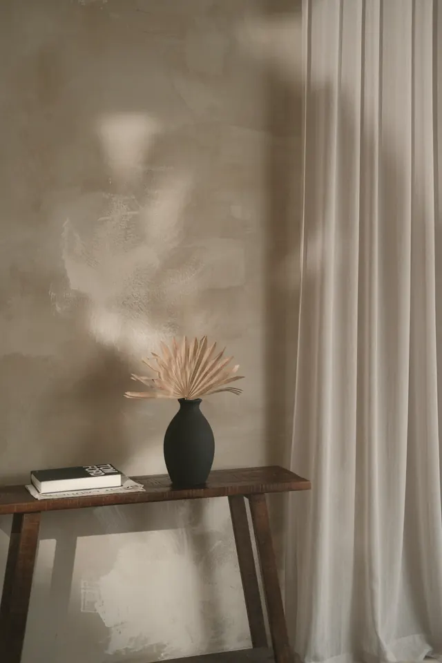 Console and black vase against a plastered wall