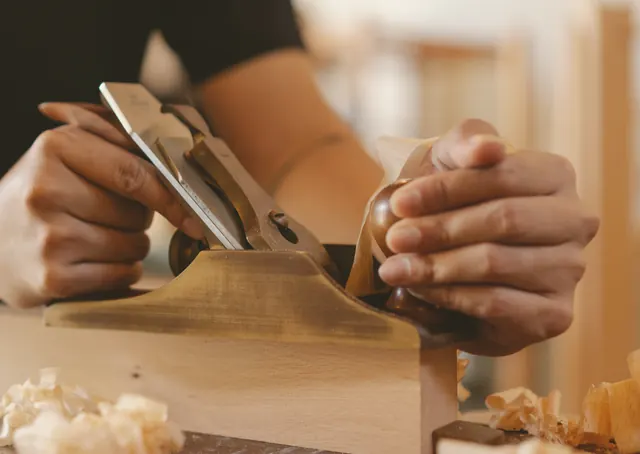 A joiner&rsquo;s hands planing a board
