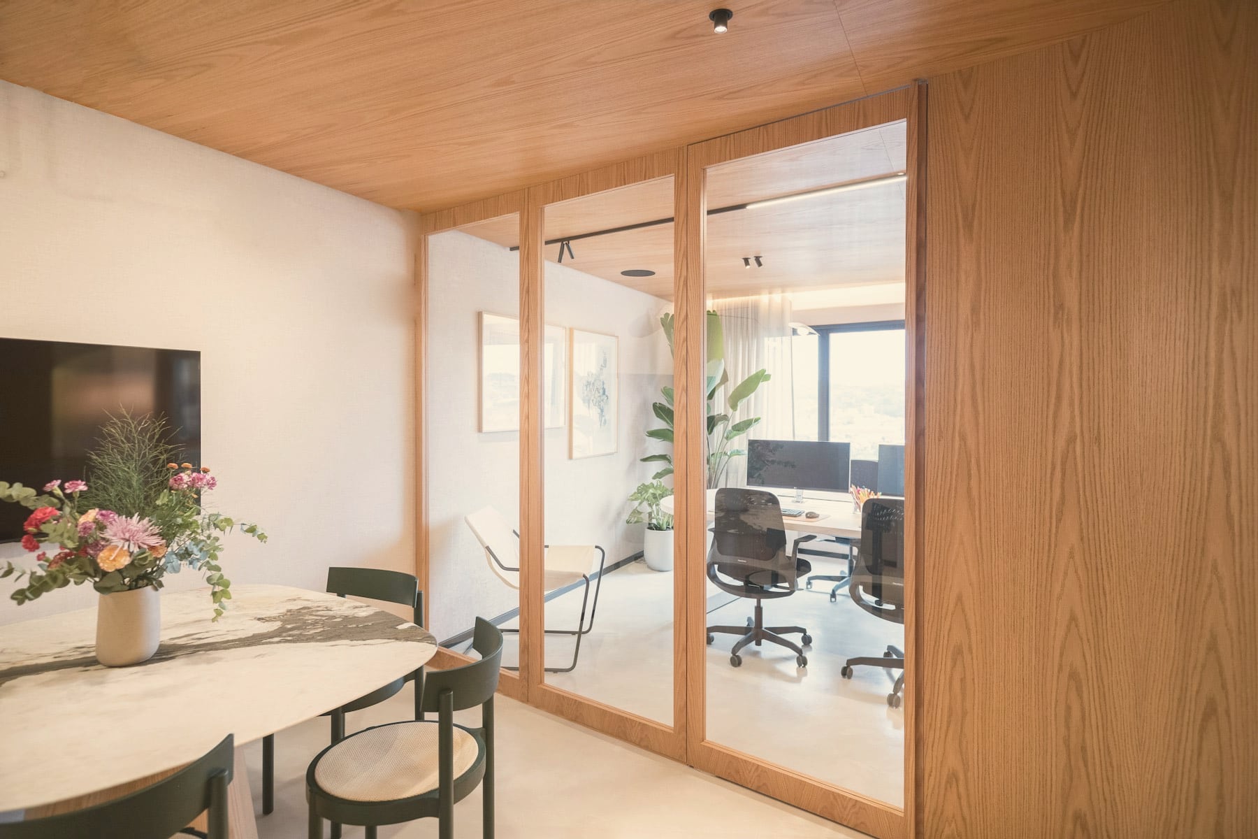 Siège d’entreprise aux parois vitrées encadrées de chêne, plafond bois et table de réunion ovale en marbre