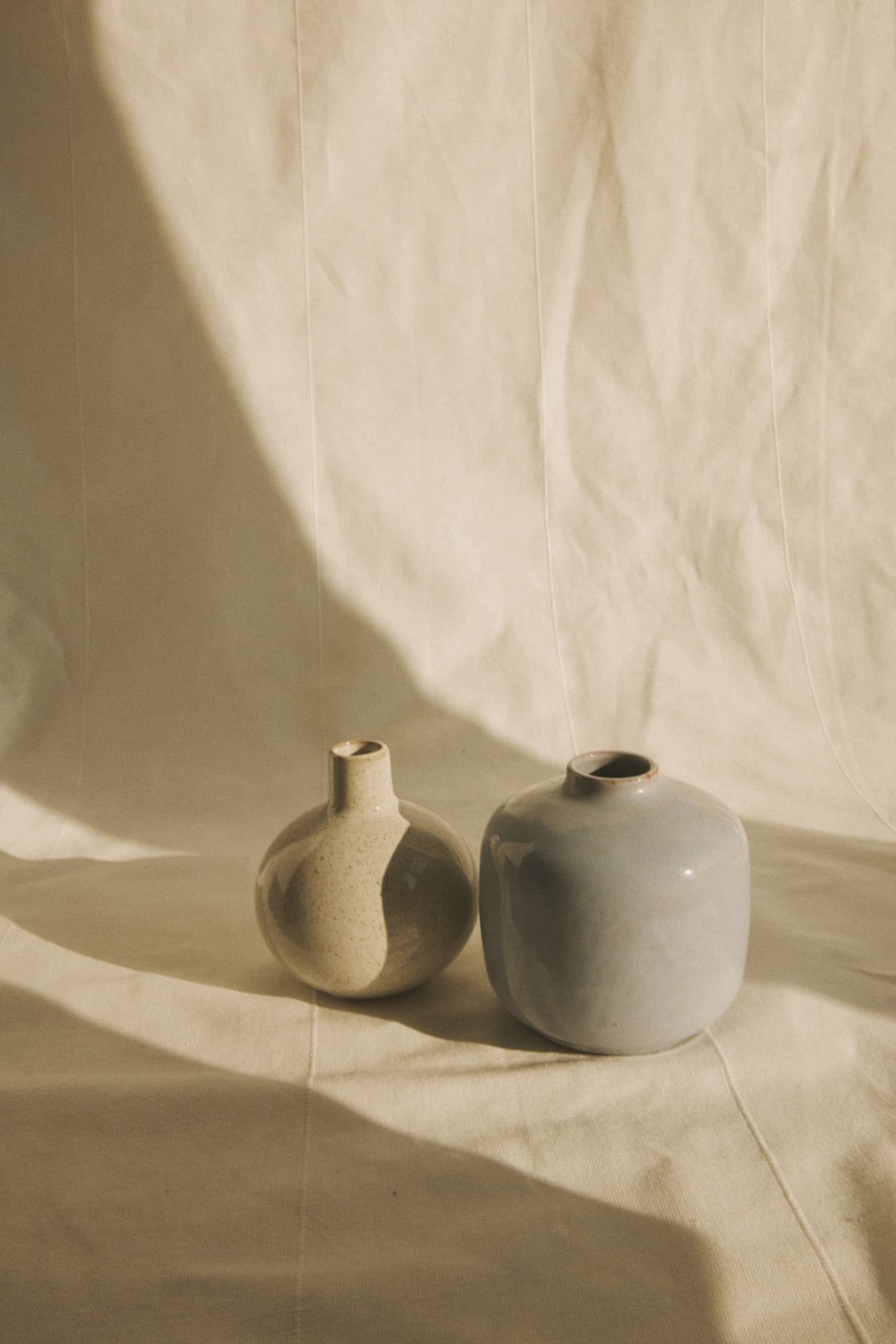 Deux petits vases en céramique mate sur un drapé de lin