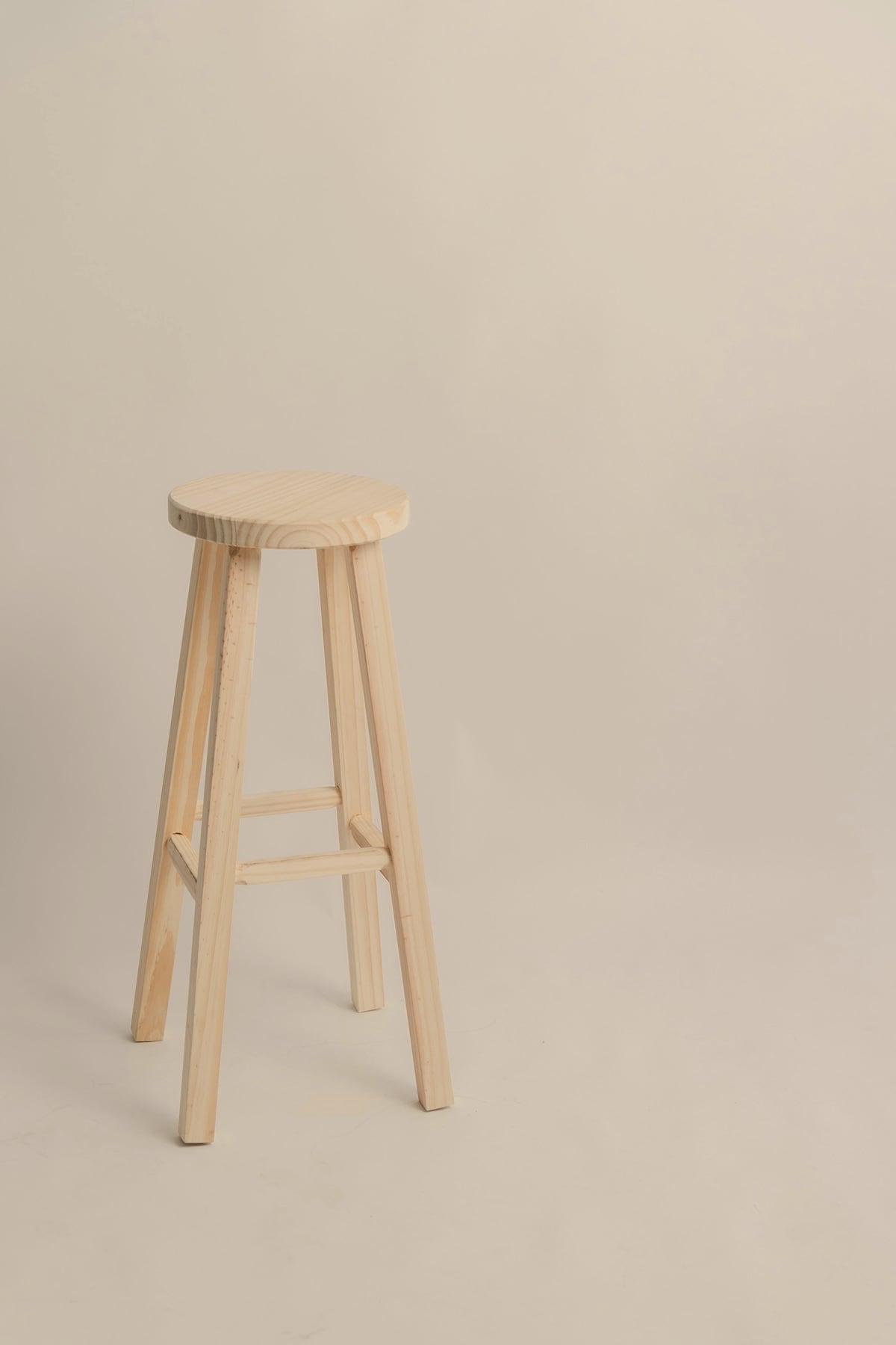 Tabouret haut en bois clair sur fond gris uni