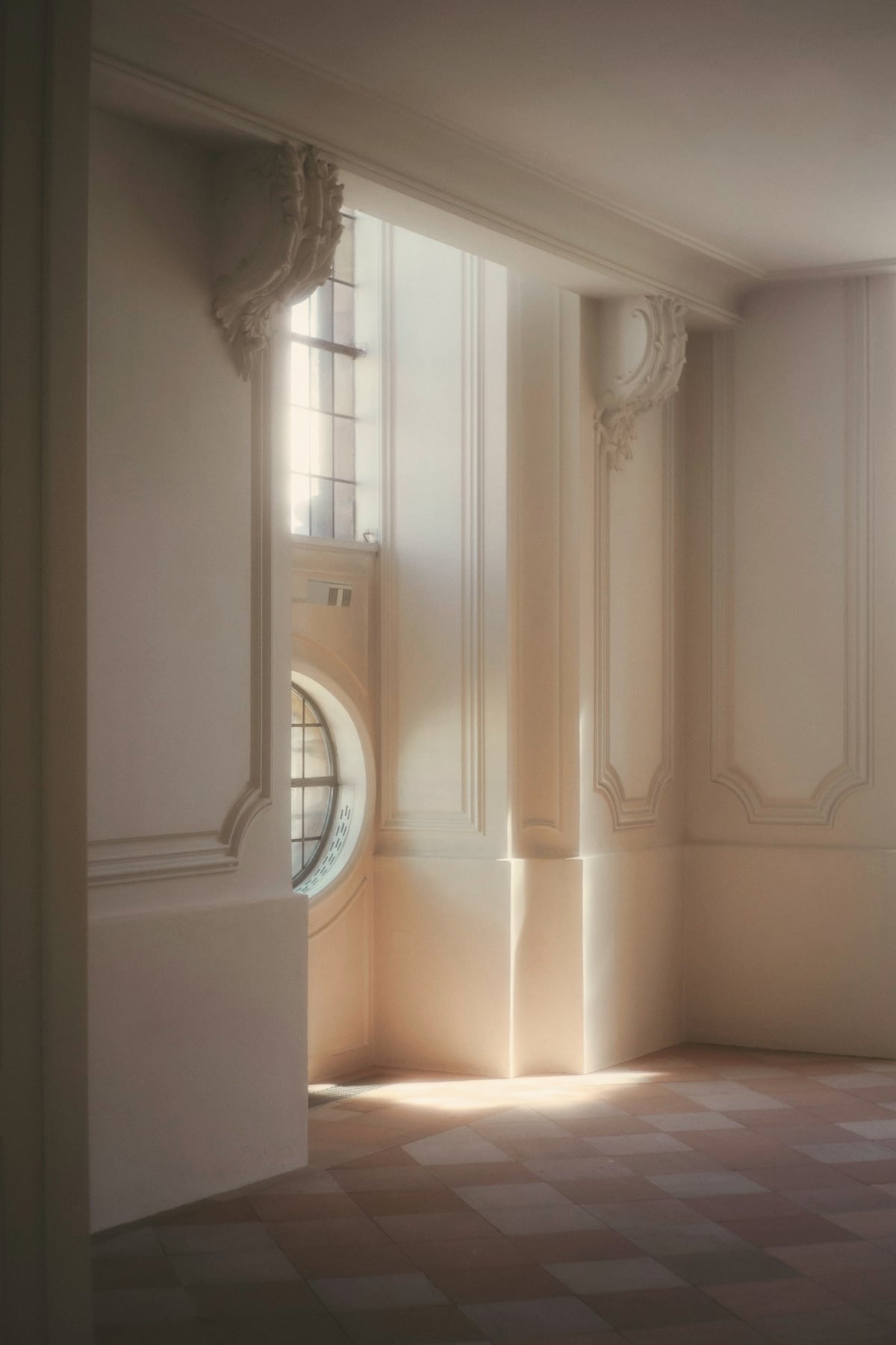 Pièce haussmannienne vide, moulures et œil-de-bœuf, lumière rasante sur le sol