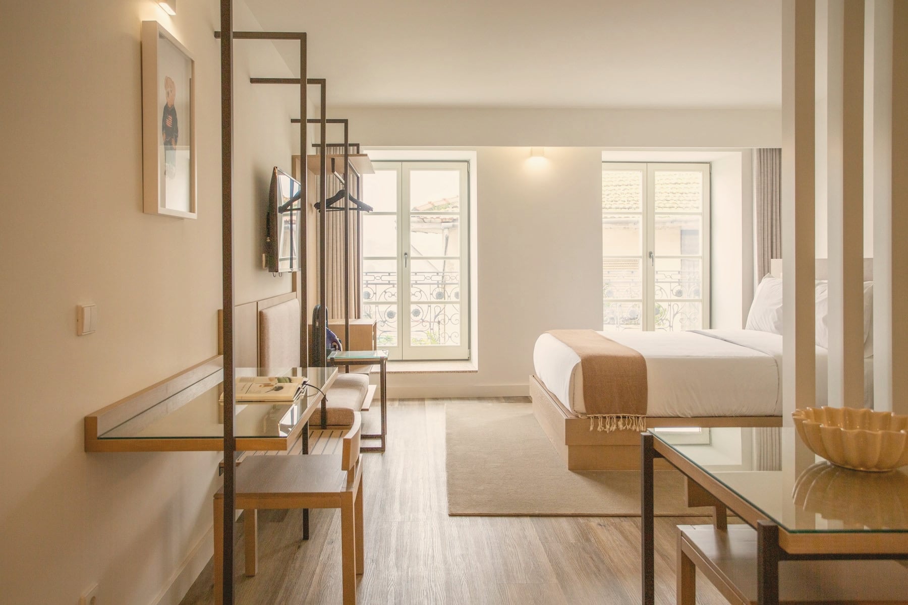 Chambre d’hôtel lumineuse : parquet, bureau en verre et bois, linge blanc