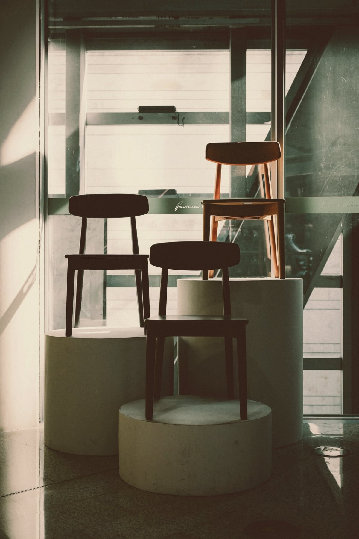 Chaises en bois présentées sur des socles cylindriques en béton