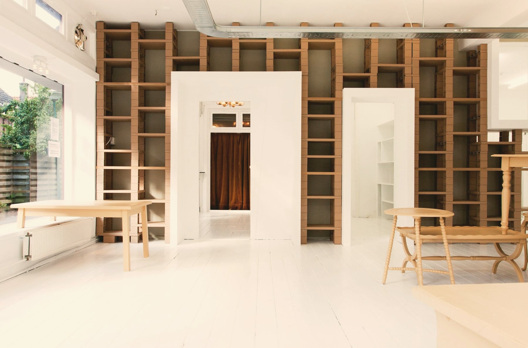 Espace de travail lumineux avec bibliothèque en bois sur toute la hauteur et tables en chêne clair